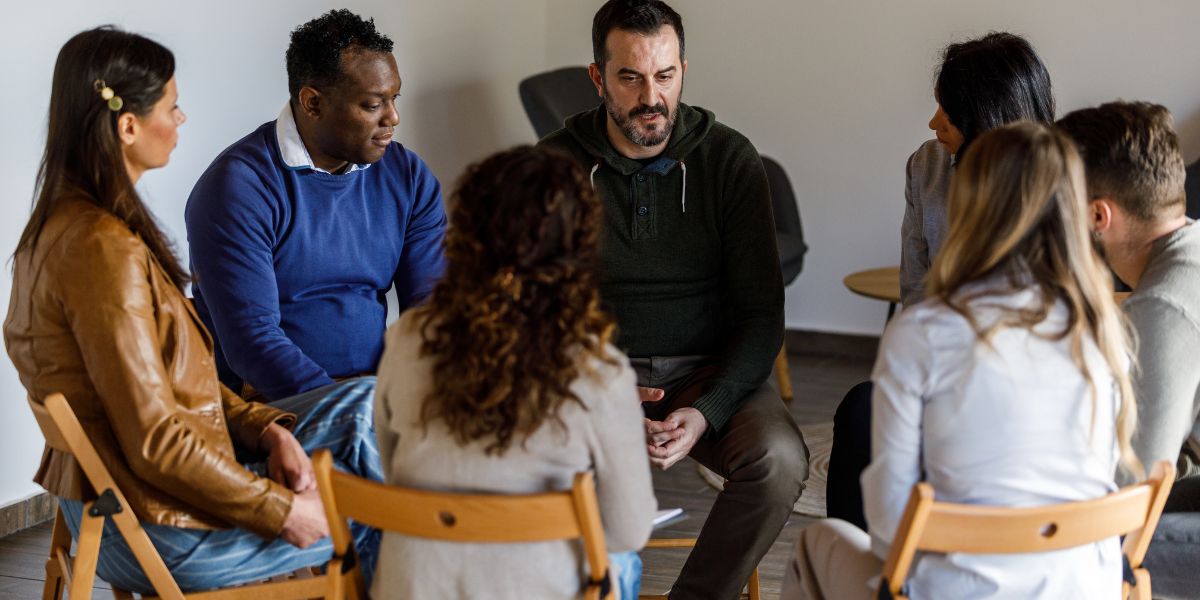 Diverse group of adults sitting in a circle during a family support meeting.