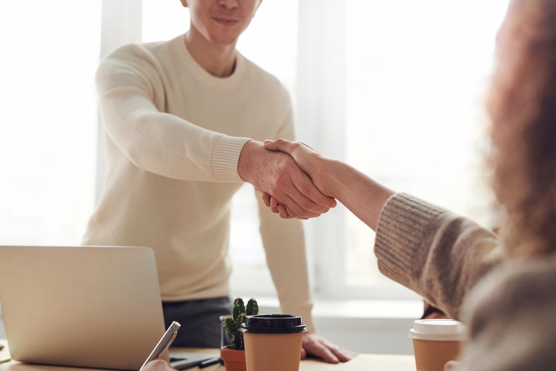 A professional real estate agent and a client shaking hands in a modern, bright setting, symbolizing a trusted partnership in protecting home equity.