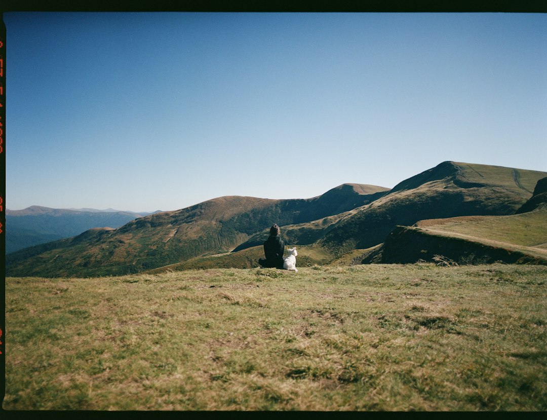A lone hiker with a single backpack peacefully looks out at a vast mountain range, illustrating the freedom of prioritizing experiences over possessions.