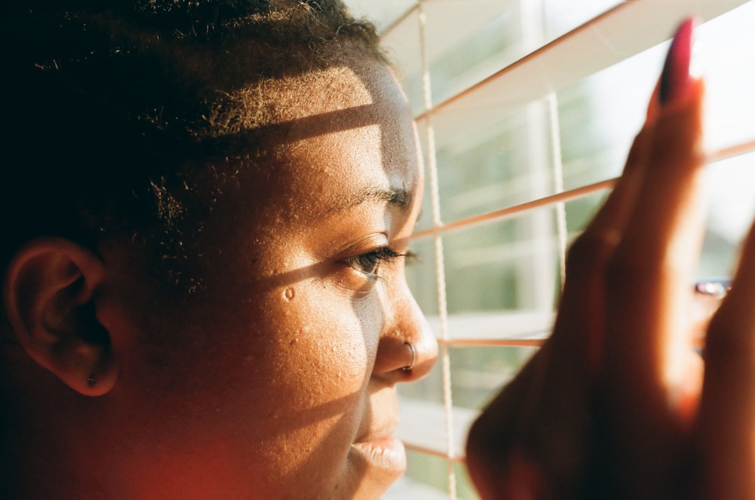 A person stands thoughtfully looking through a large, clean window at a clear view, symbolizing the clarity and new perspective of financial sobriety.